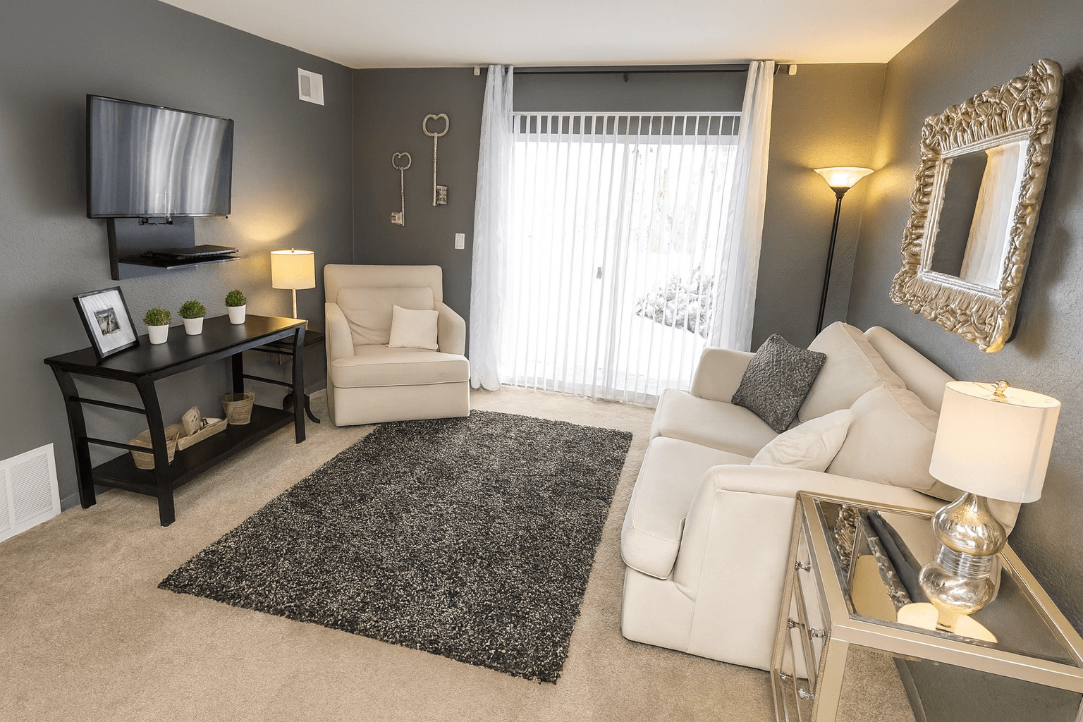 A living room with a white couch, a black coffee table, and a large mirror on the wall.